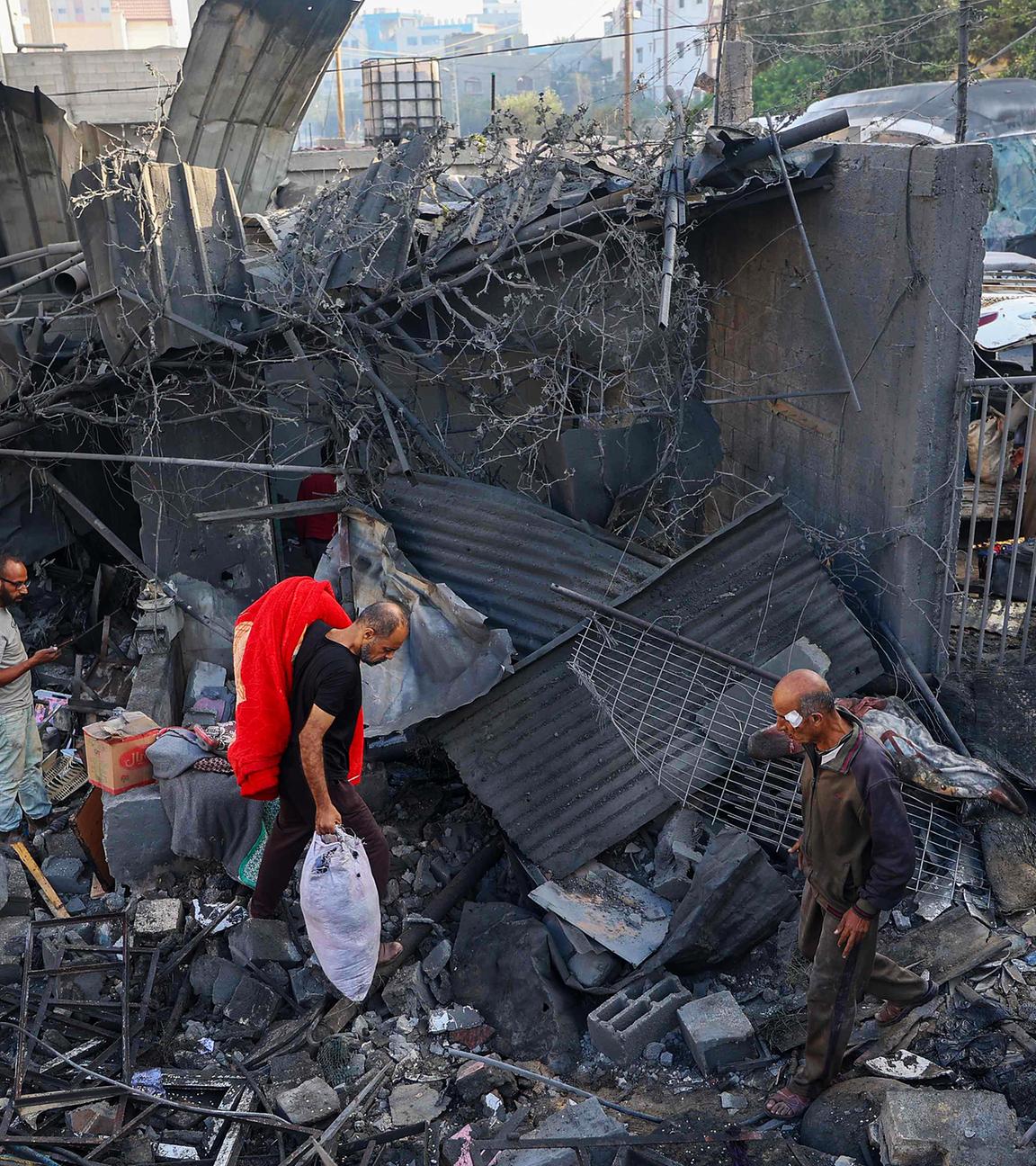 Menschen gehen am 29.102025 durch die Trümmer eines Hauses, das bei einem israelischen Angriff in Nuseirat im zentralen Gazastreifen zerstört wurde