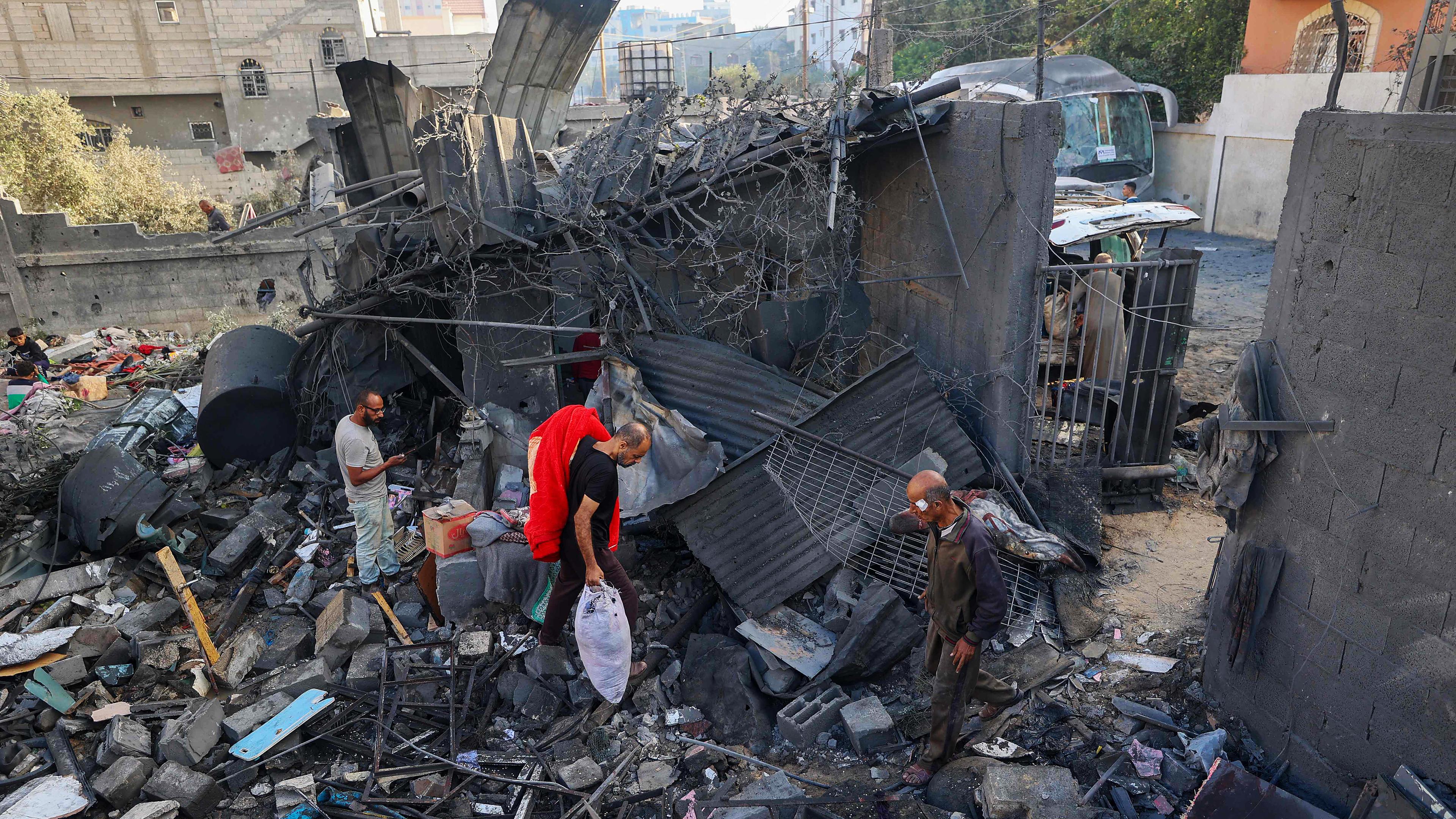 Menschen gehen am 29.102025 durch die Trümmer eines Hauses, das bei einem israelischen Angriff in Nuseirat im zentralen Gazastreifen zerstört wurde