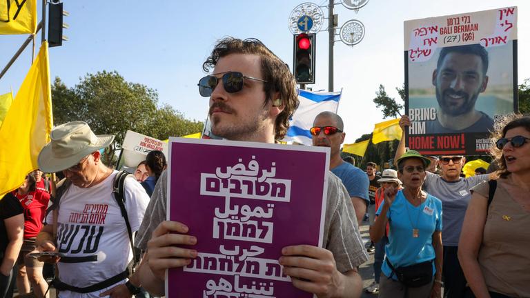 Protesters lift placards during a rally calling for an end of the war in Gaza and a return of Israelis held hostage since 2023 in the besieged Palestinian territory, in front of the prime minister's office in Jerusalem on August 26, 2025. 