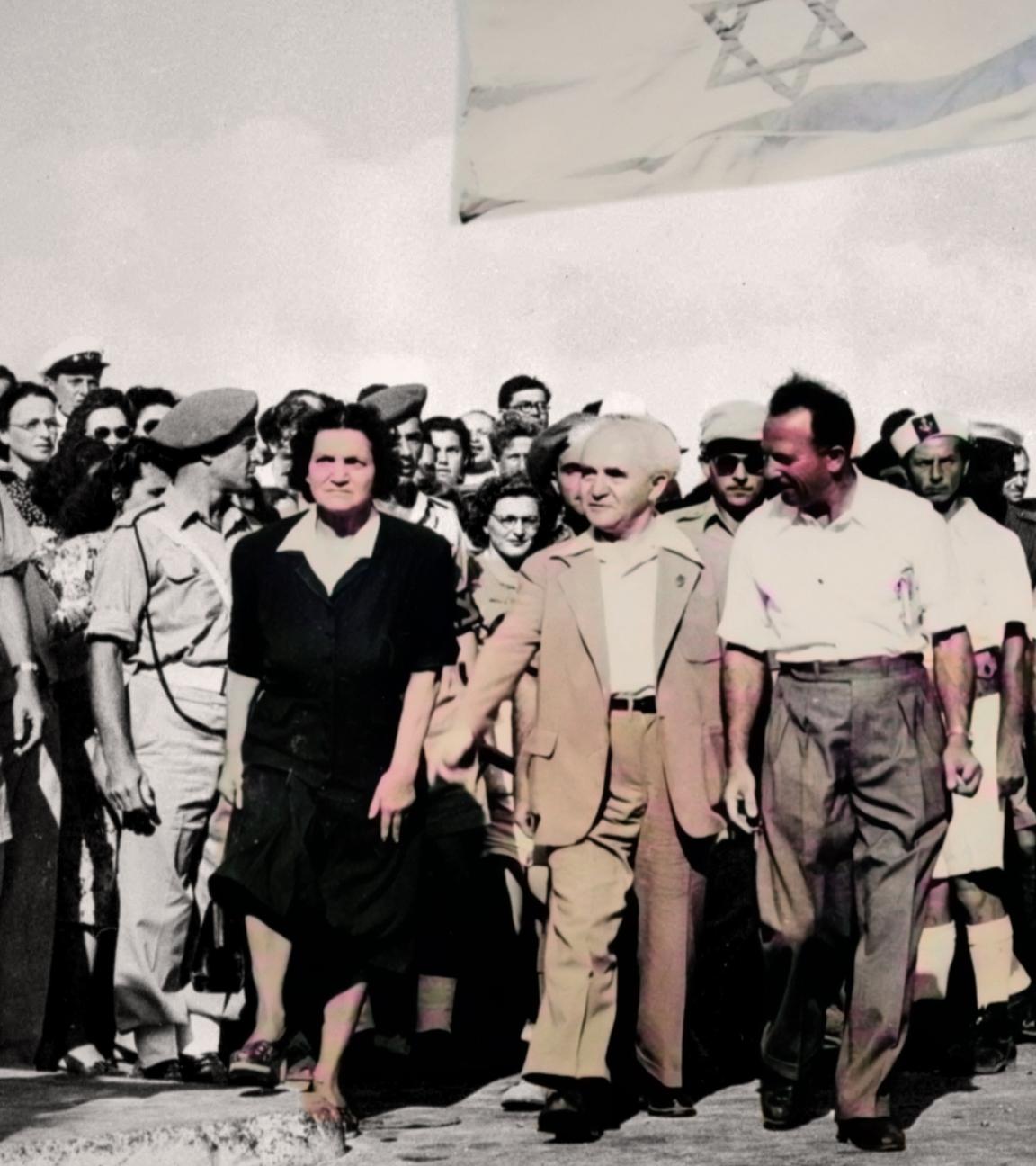 Koloriertes Schwarz-Weiß-Foto vom 3. Juli 1948: Israels Premierminister David Ben Gurion läuft mit seiner Frau und den letzten britischen Soldaten auf den Haifa Docks an einer kleinen Abteilung der israelischen Marine vorbei.