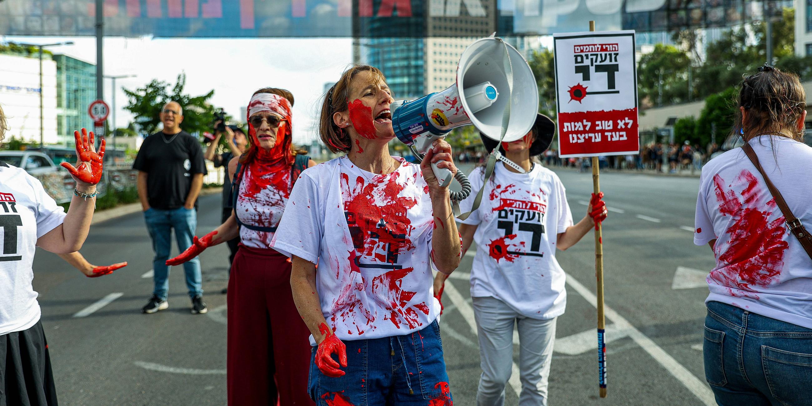 Mütter israelischer Soldaten, die im Gazastreifen kämpfen, protestieren (Mai 2024).  Sie haben rote Farbe am Körper, die Blut darstellen soll.