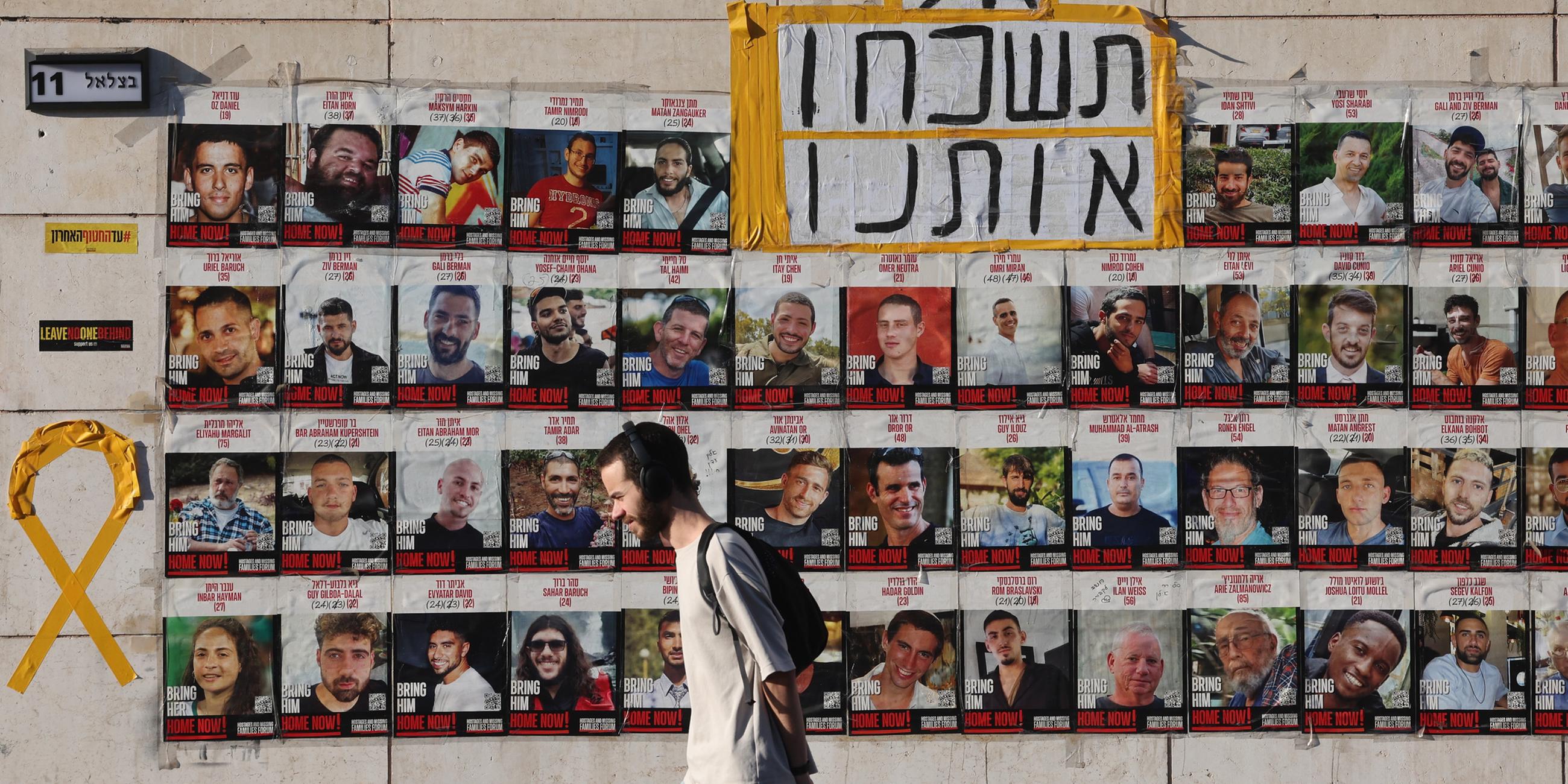 Eine Person läuft an den Bildern der Israelischen Geiseln vorbei die noch immer von der Hamas in Gaza gefangen gehalten werden. (Archiv)