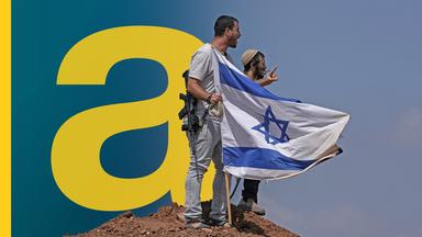 Zwei Männer neben einer israelischen Flagge, die im Boden steckt. 