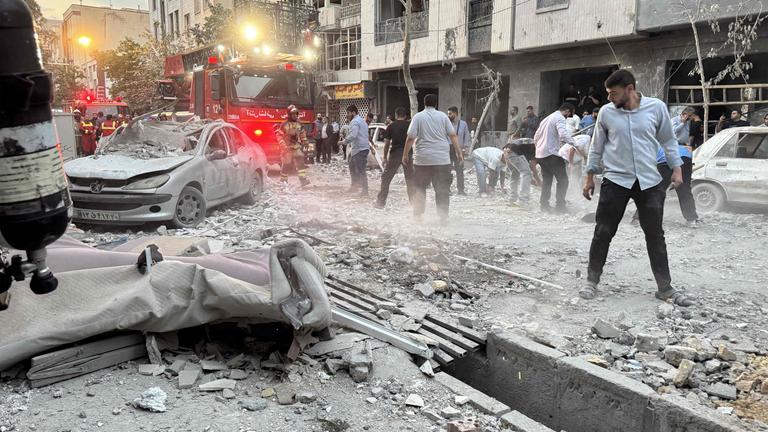 Menschen und Ersthelfer versammeln sich vor einem Gebäude, das am 13. Juni 2025 in Teheran von einem israelischen Angriff getroffen wurde. 