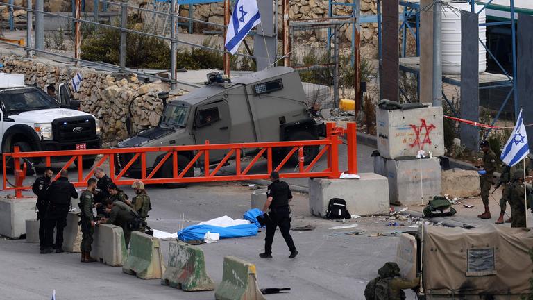 Israelische Sicherheitskräfte stehen neben den Leichen zweier palästinensischer Männer an einem Kontrollpunkt nahe Hebron