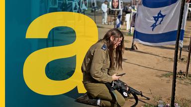 Eine Frau mit einem Maschinengewehr, die vor einer israelischen Flagge kniet.