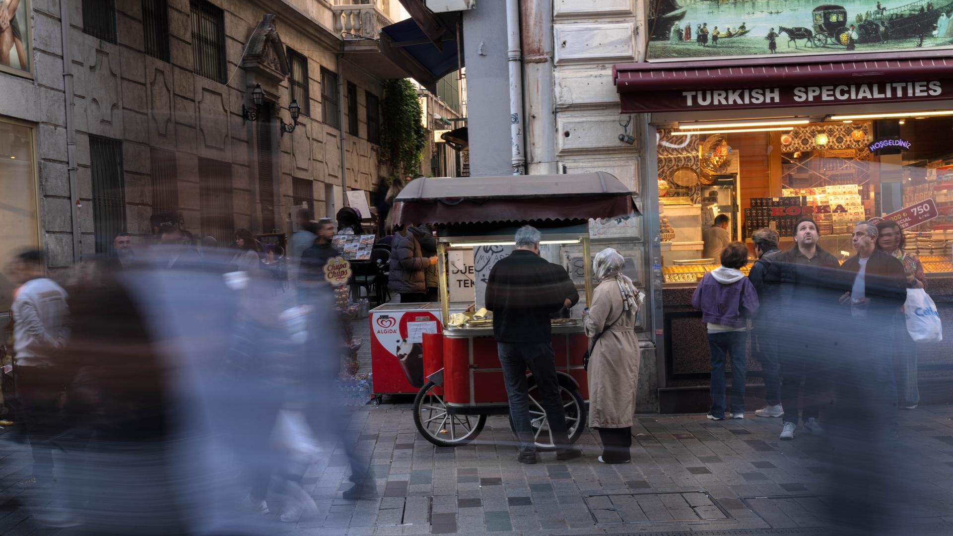  Istanbul: Menschen gehen an einem Imbissstand auf der Istiklal-Straße vorbei, einer belebten Fußgängerzone, die für ihr Street Food und ihren historischen Charme bekannt ist, 
