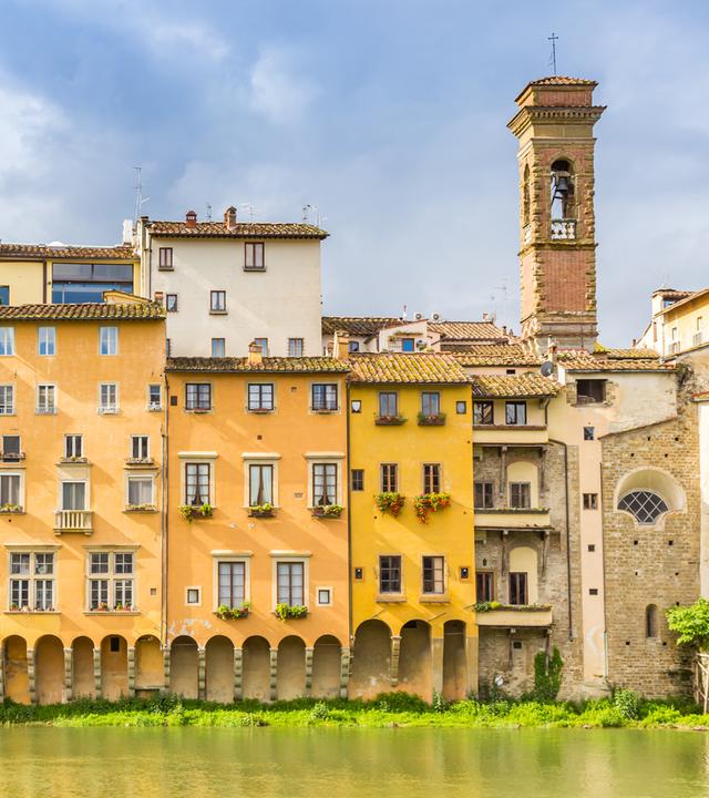 Bunte historische Häuser und Kirchturm stehen am Fluss Arno in Florenz.