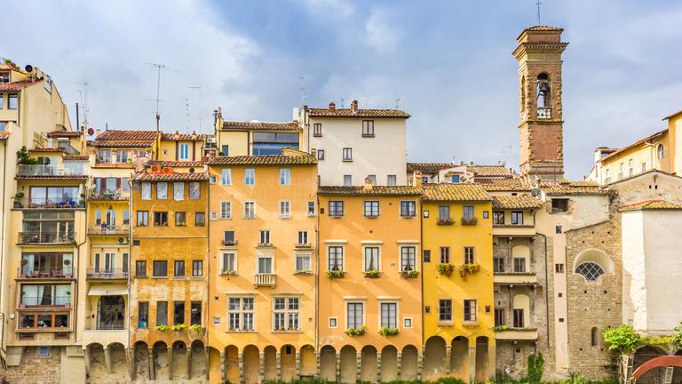 Bunte historische Häuser und Kirchturm stehen am Fluss Arno in Florenz.