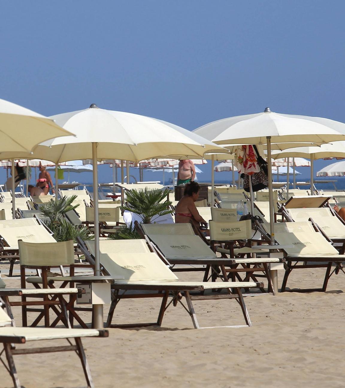 Italien, Rimini: Überwiegend leere Sonnenliegen stehen am Strand des Badeortes.