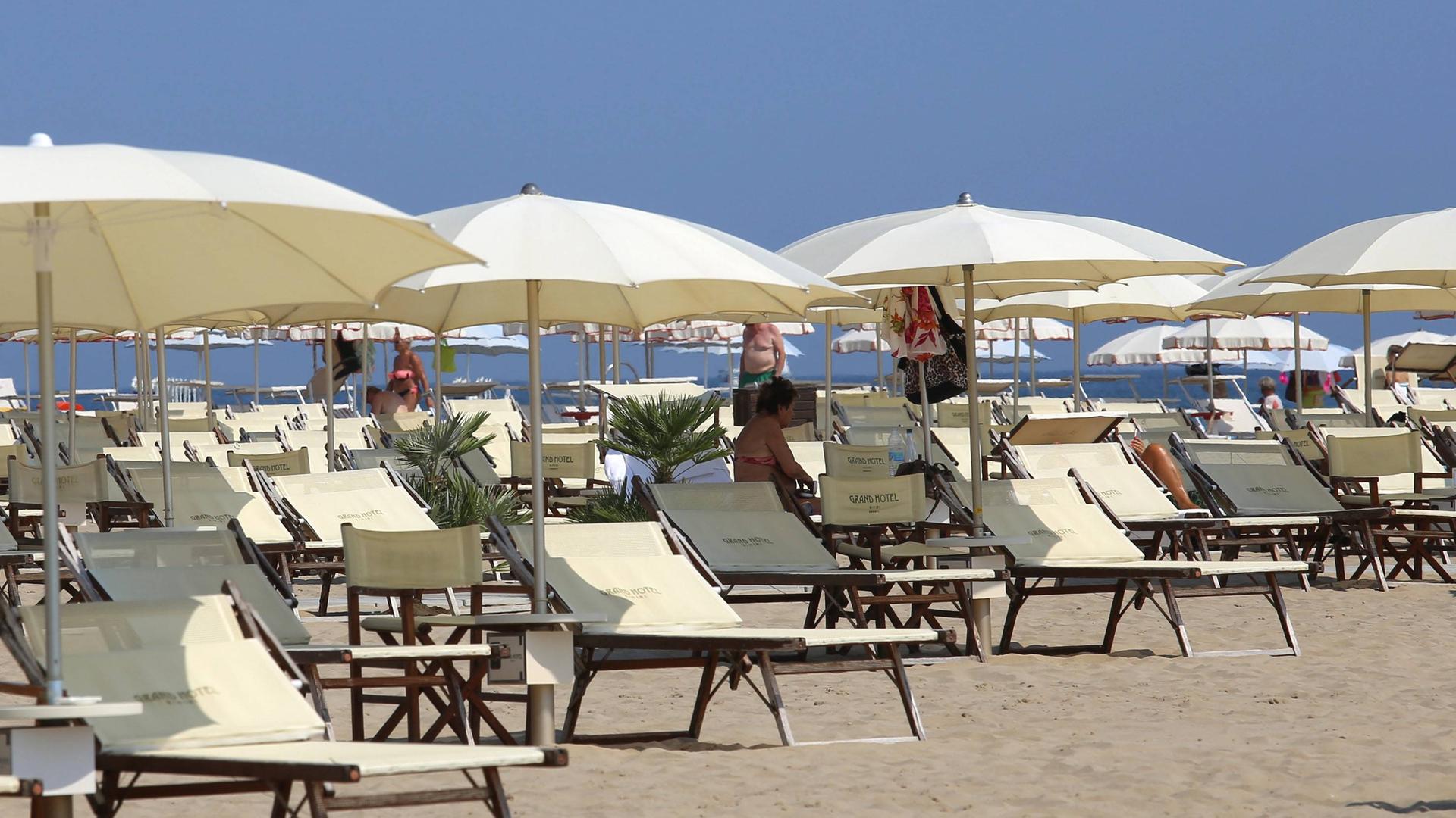 Italien, Rimini: Überwiegend leere Sonnenliegen stehen am Strand des Badeortes.