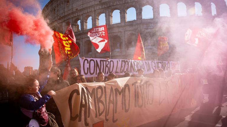 12.12.2025, Italien, Rom: Teilnehmer einer Demonstration unter anderem gegen das Haushaltsgesetz der Regierung sind in Rom auf einer Straße unterwegs.