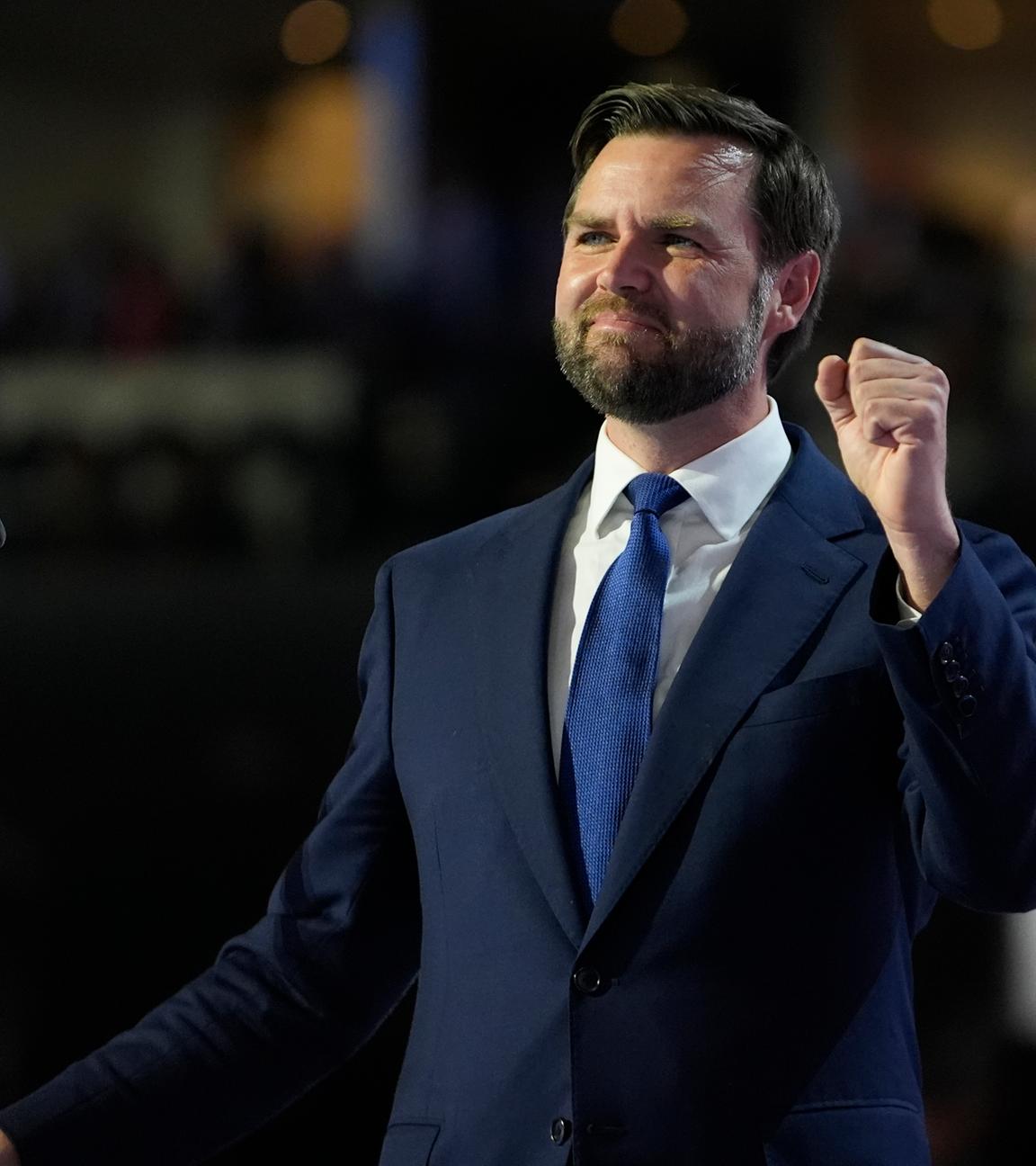 J.D. Vance steht im Anzug hinter einem Rednerpult und hebt eine geballte Faust in die Luft. 