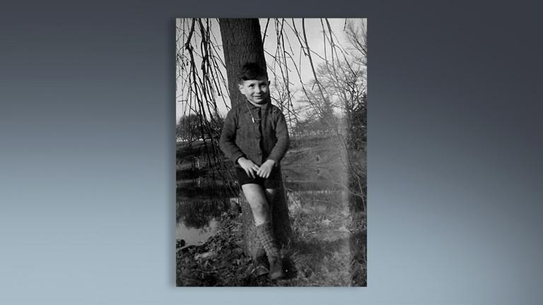 Jack Offen steht als Kind nach Kriegsende vor einem Baum.