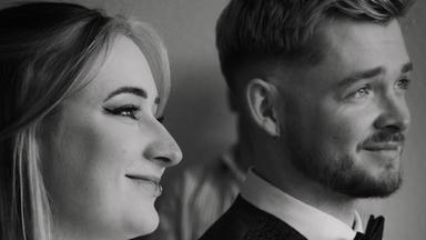 Zwei Erwachsene Personen, links eine Frau im Hochzeitskleid, rechts ein Mann, beide sitzen.