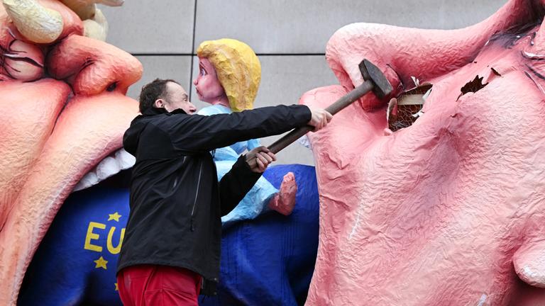 Der Wagenbauer Jacques Tilly schlägt mit einem Vorschlaghammer auf eine Putin-Figur ein die auf seinem eigenen Mottowagen während des Rosenmontagszugs in Düsseldorf am 17.02.2026 gezeigt wird.