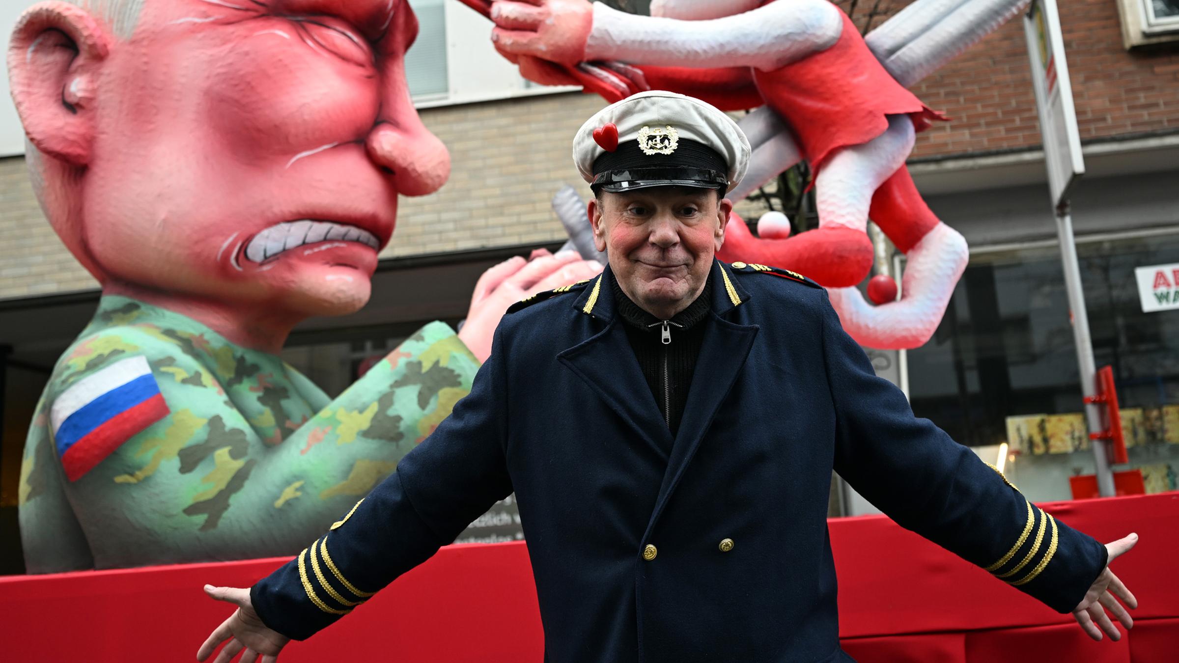 Jacques Tilly, Wagenbauer, steht vor dem Mottowagen, auf dem eine Skulptur des russischen Präsidenten Wladimir Putin die Düsseldorfer Karnevalsfigur Hoppeditz aufspießt. (Archiv)