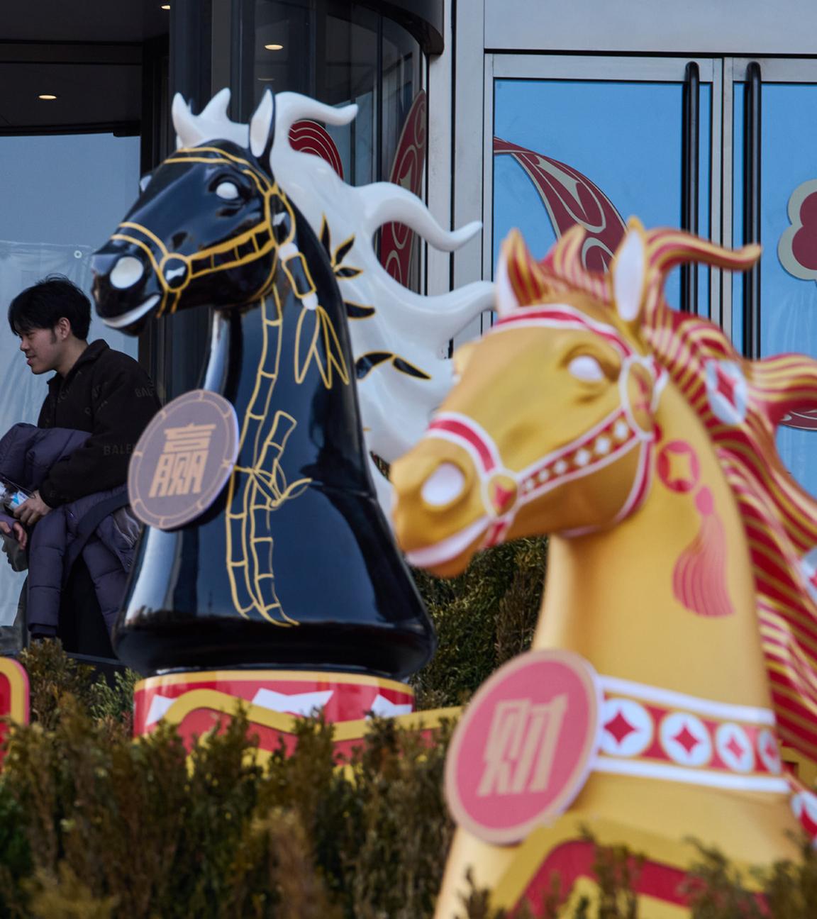 Besucher eines Einkaufszentrums in Peking gehen an einer Dekoration zum chinesischen Jahr des Feuerpferdes vorbei.