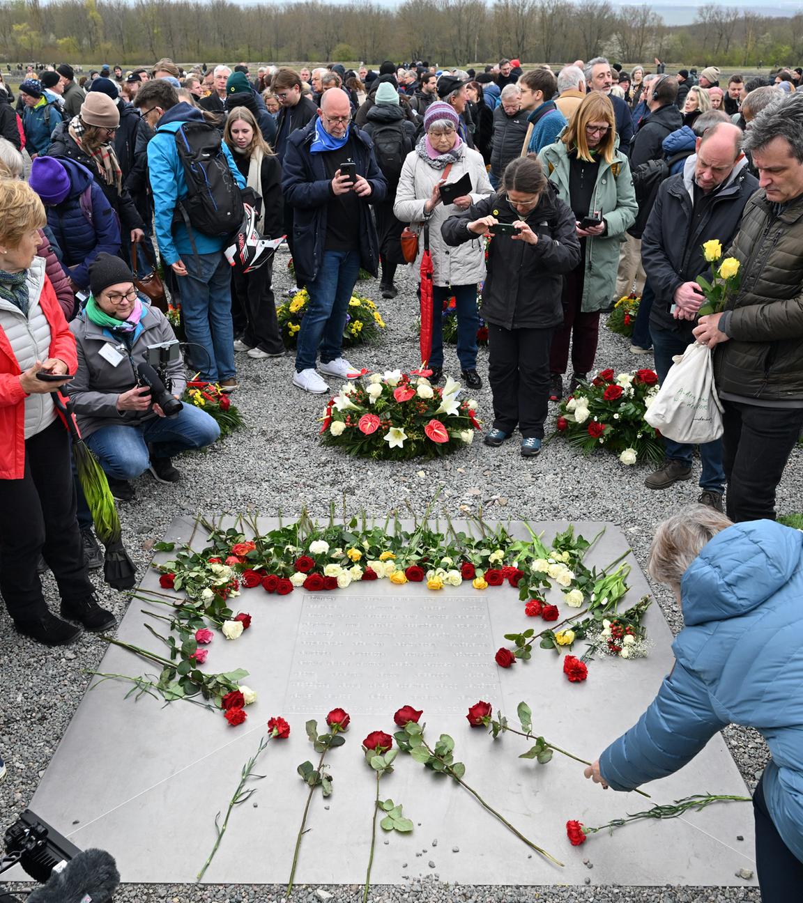 12.04.2026, Thüringen, Weimar: Blumen werden auf einer Gedenktafel niedergelegt beim Festakt zum 81. Jahrestag der Befreiung des Konzentrationslagers Buchenwald.