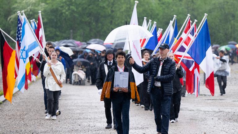 Bayern, Dachau: Teilnehmer der Gedenkfeier zum 80. Jahrestag der Befreiung der Häftlinge des KZ Dachau gehen über das Gelände der Gedenkstätte.