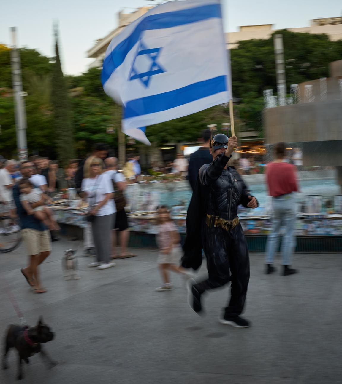 Ein als «Batman» verkleideter Mann schwenkt eine israelische Fahne, während Menschen Fotos von Israelis betrachten, die beim Terrorangriff der Hamas getötet wurden. Am 7. Oktober 2023 griffen Kämpfer der radikalislamischen Hamas Israel an, töteten zahlreiche Menschen und verschleppten Geiseln in den Gazastreifen.