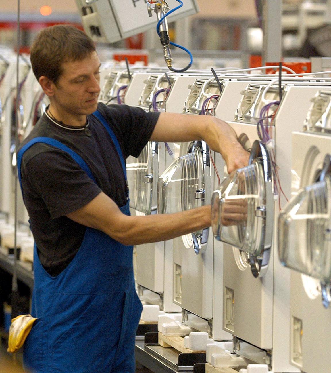 An einer Produktionsstraße für Waschautomaten arbeitet ein Miele-Mitarbeiter.