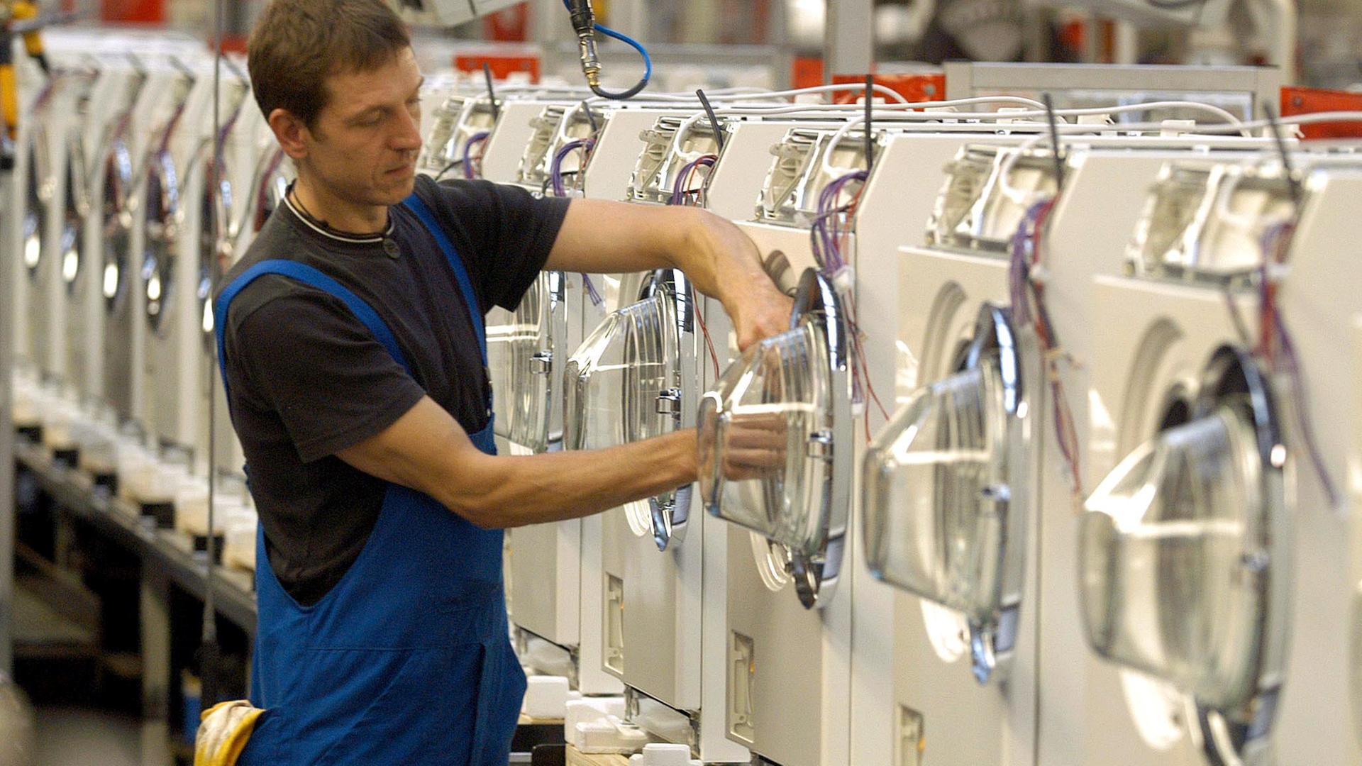 An einer Produktionsstraße für Waschautomaten arbeitet ein Miele-Mitarbeiter.