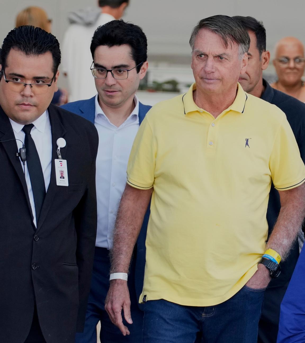 Der brasilianische Politiker Jair Bolsonaro während eines Freigangs in seinem Hausarrest, umringt von Security und Angestellten.