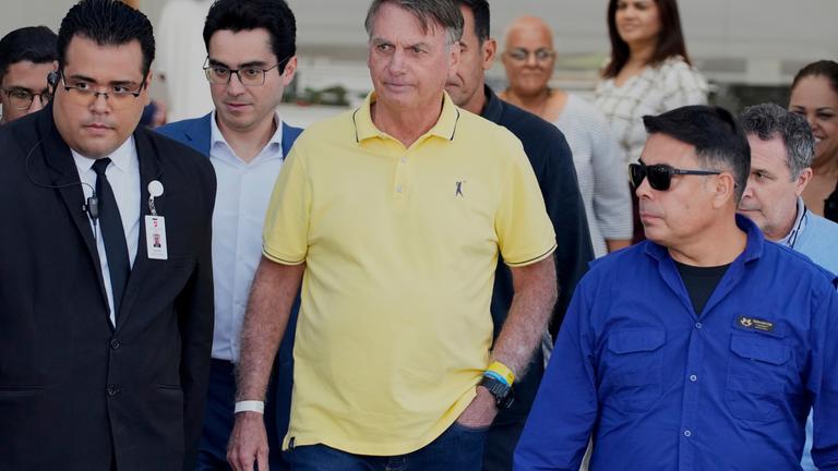 Der brasilianische Politiker Jair Bolsonaro während eines Freigangs in seinem Hausarrest, umringt von Security und Angestellten.