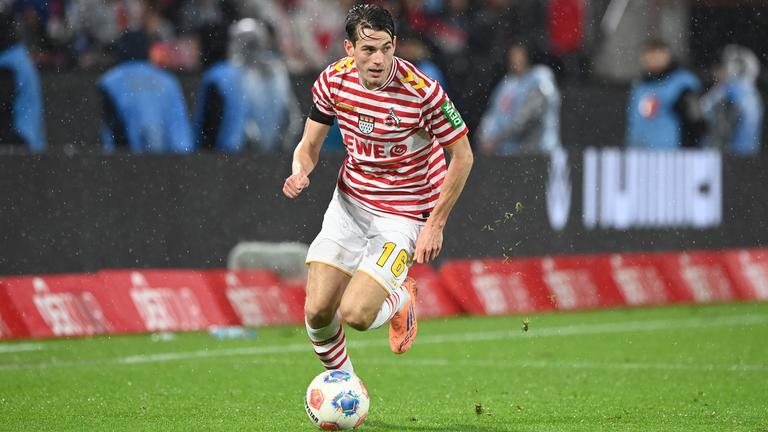 Kölns Spieler Jakub Kaminski läuft beim Spiel gegen den Hamburger SV im rot-weiß gestreiften Karnevalstrikot des 1. FC Köln mit dem Ball vor dem rechten Fuß über den Rasen.