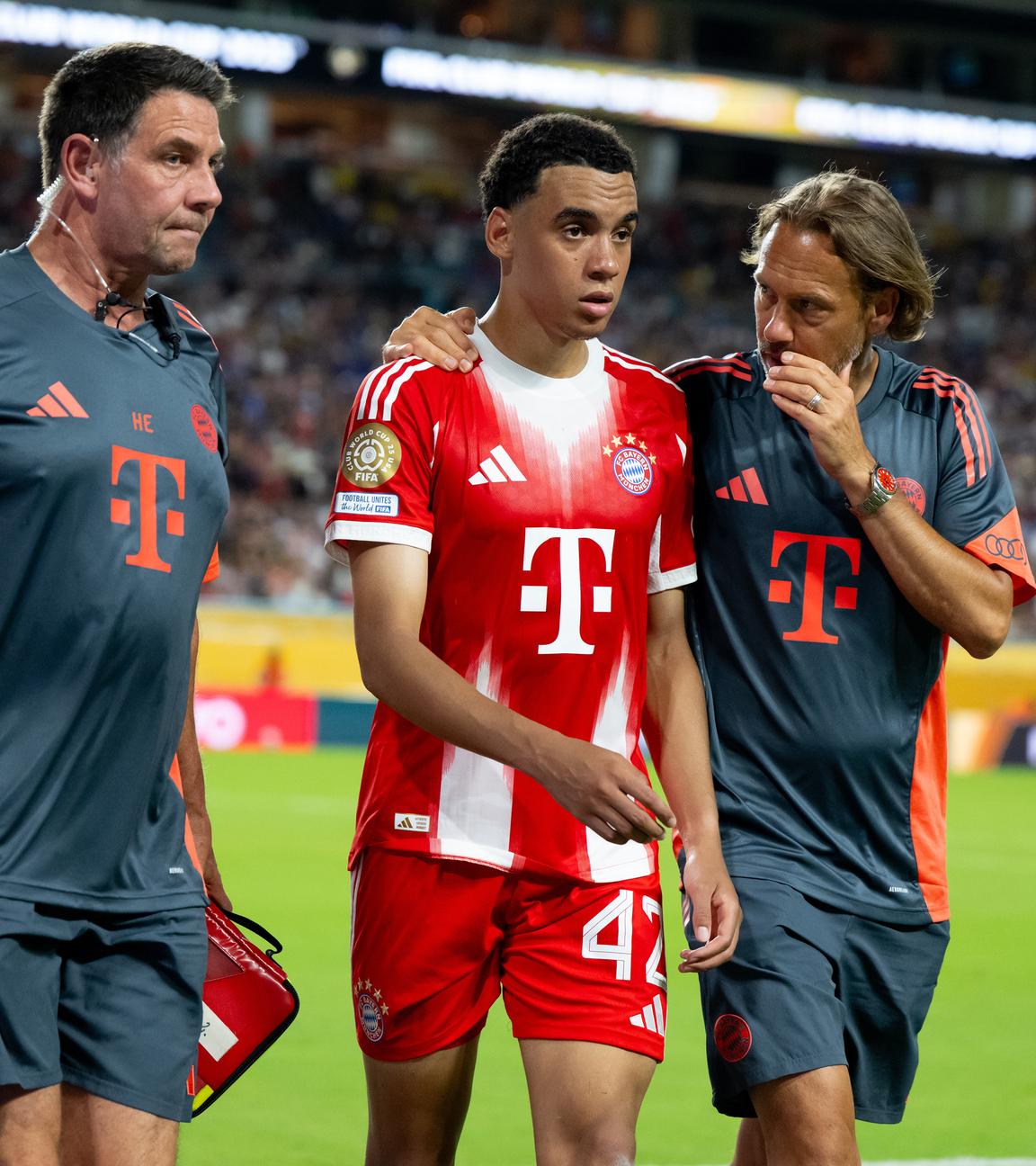 Fußballer Jamal Musiala von Bayern München, in der Mitte, wird nach seiner Behandlung am 20.06.2025 auf dem Spielfeld ausgewechselt. 