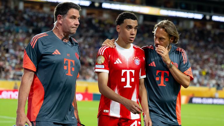 Fußballer Jamal Musiala von Bayern München, in der Mitte, wird nach seiner Behandlung am 20.06.2025 auf dem Spielfeld ausgewechselt. 