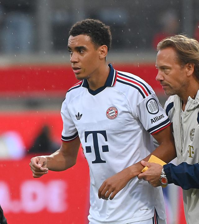 Jamal Musiala wird von Dr. Peter Ueblacker (Mannschaftsarzt FCB) vom Platz geführt, aufgenomme  18.08.2026