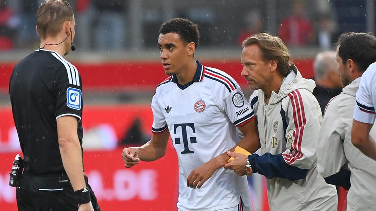 Jamal Musiala wird von Dr. Peter Ueblacker (Mannschaftsarzt FCB) vom Platz geführt, aufgenomme  18.08.2026