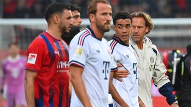 Dr. Peter Ueblacker (Mannschaftsarzt FCB) und Harry Kane (links) begleiten Jamal Musiala vom Platz