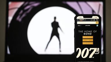 Diese am 23. Februar 2025 in London erstellte Fotoillustration zeigt die Amazon.co.uk-App „The Home Of Bond“ auf einem Handydisplay neben einem Foto auf einem Laptop-Bildschirm.