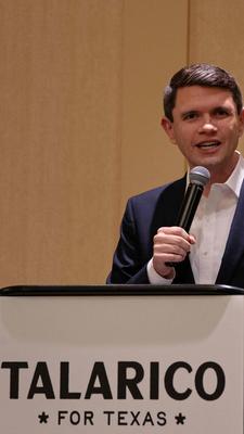 James Talarico steht auf einem Podest und spricht in ein Mikrofon.