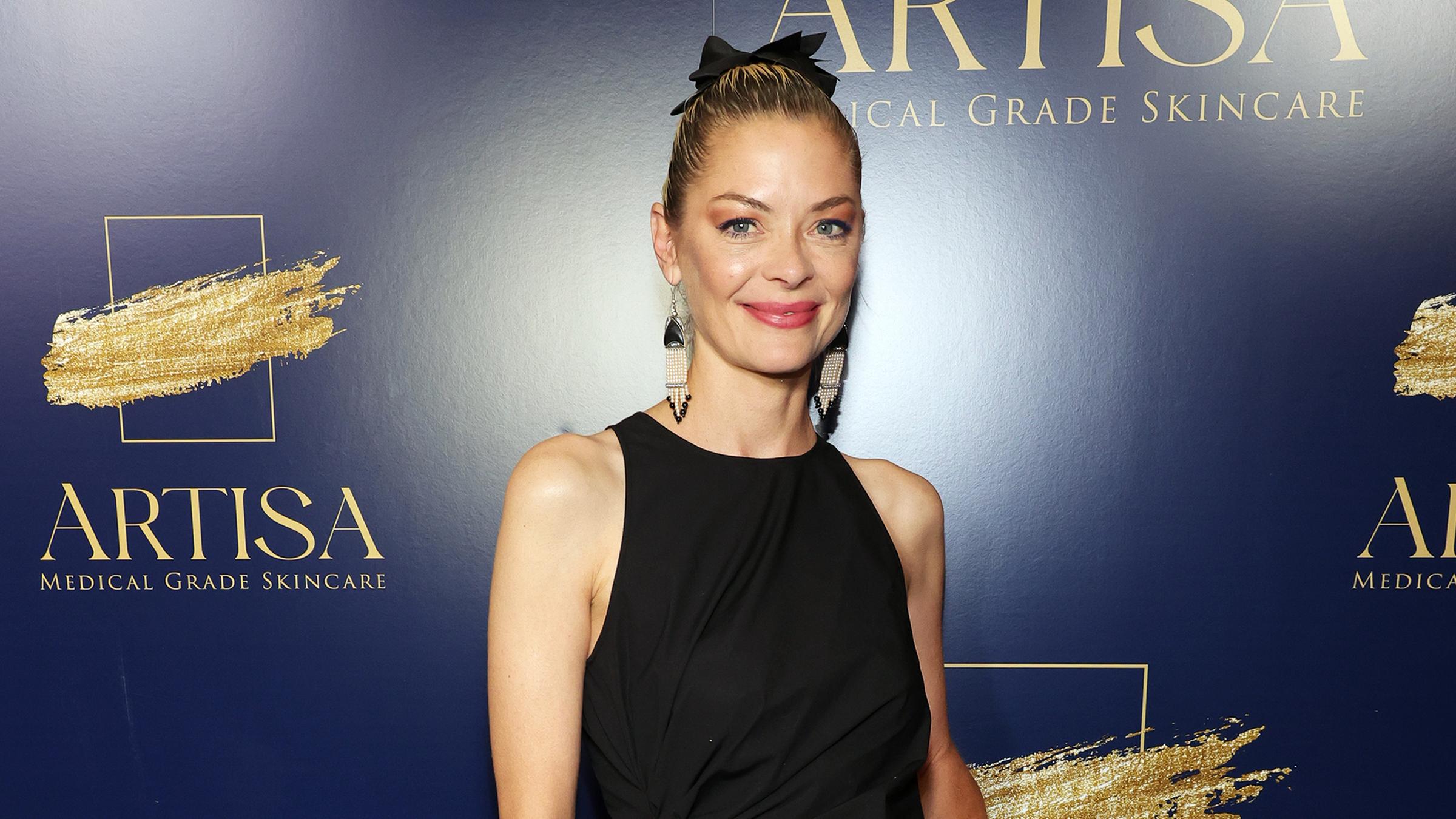 Jamie King posiert bei einem Event in einem schwarzen Kleid für die Fotografen.