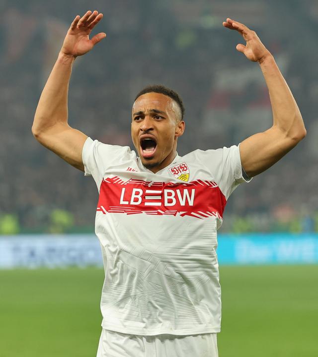 Fußballspieler Jamie Leweling im Trikot des VfB Stuttgart wirft im Spiel die Arme nach oben.