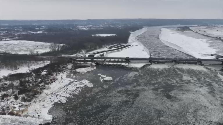 Aus der Vogelperspektive eine Landschaft und ein Fluss im Winter zu erkennen. Der Schnee schient zu schmelzen