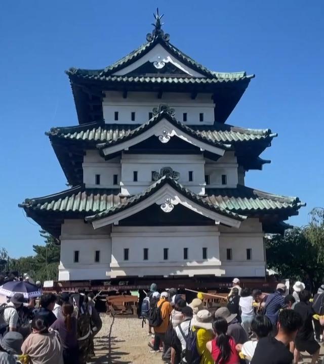 Freiwillige in Japan ziehen mit einem Seil an einem Turm, um ihn an einen anderen Standort zu bringen.