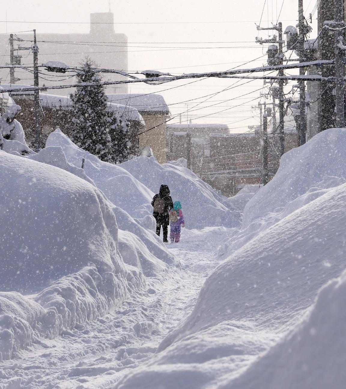 Menschen gehen auf einer Straße nach starkem Schneefall in Sapporo, Hokkaido, Japan.
