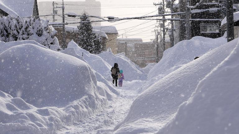 Menschen gehen auf einer Straße nach starkem Schneefall in Sapporo, Hokkaido, Japan.