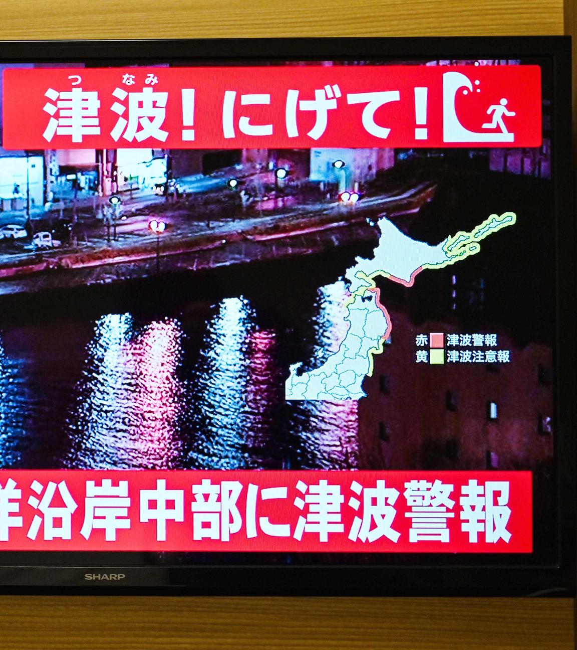 Im japanischen Fernsehen werden Warnungen für die Bewohner an den Küsten ausgespielt. Die Menschen sollen ihre Häuser verlassen.