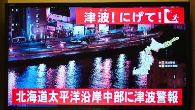 Im japanischen Fernsehen werden Warnungen für die Bewohner an den Küsten ausgespielt. Die Menschen sollen ihre Häuser verlassen.
