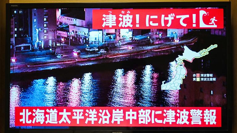 Im japanischen Fernsehen werden Warnungen für die Bewohner an den Küsten ausgespielt. Die Menschen sollen ihre Häuser verlassen.