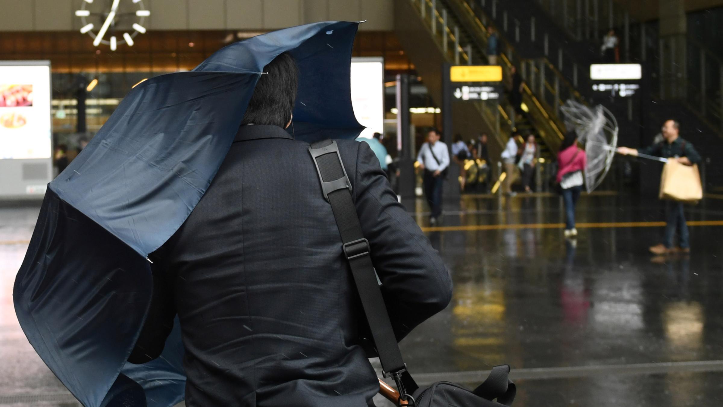 Passanten in Osaka kämpfen im Unwetter mit ihren Regenschirmen.