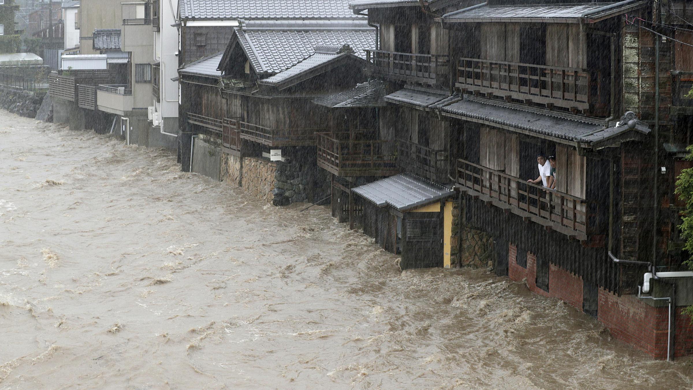 Zwei Anwohner beobachten eine überflutete Straße in Ise