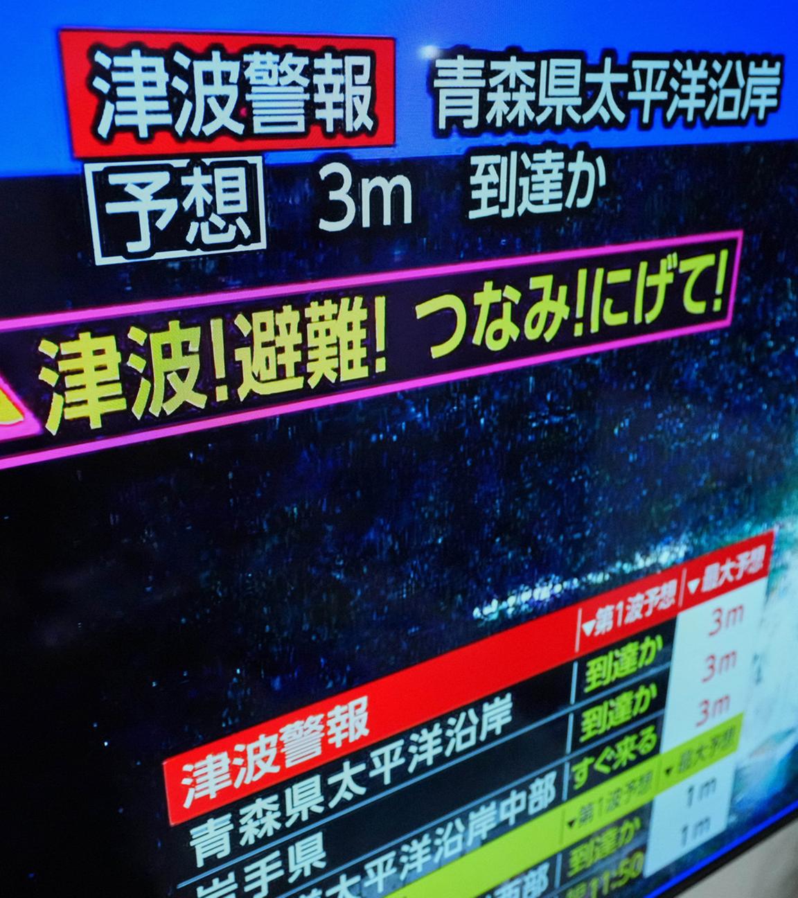 In Yokohama, nahe Tokio, wird am Montag, 8. Dezember 2025, nach einem starken Erdbeben vor der Nordküste Japans eine Tsunami-Warnung auf einem Fernsehbildschirm angezeigt.