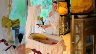 Die schwangeren Jeanette Biedermann steht vor eine Babybett.